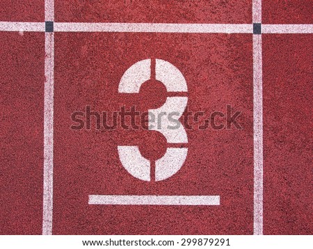 Number three. White track number on red rubber racetrack, texture of running racetracks in small stadium