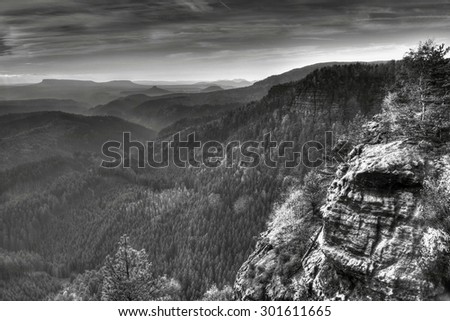 Mountain arrange in black and white color. Forest vally below sharp sandstone rocks. Black and white photo