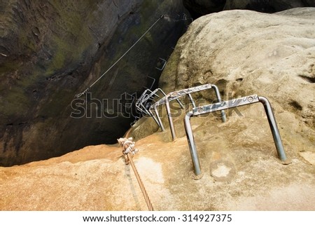 Climbers ladder. Iron twisted rope fixed in block by screws snap hooks. The rope end anchored into sandstone rock.