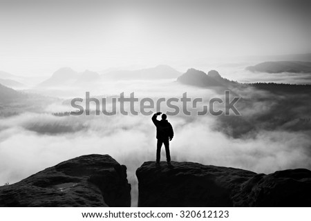 Man stands on the peak of sandstone rock in national park Saxony Switzerland and watching to Sun. Beautiful moment the miracle of nature. Black and white photo