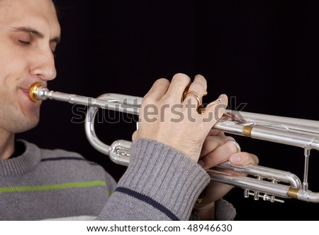 Close up view of real  trumpet player male playing on silver trumpet, focus on hand, on black isolated