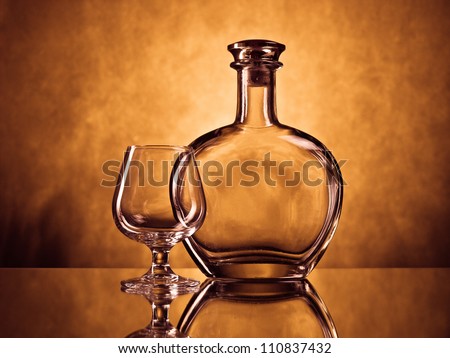 Empty cognac bottle and a cognac glass on grunge background