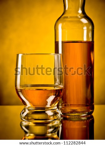 Glass of whiskey next to a bottle of whiskey