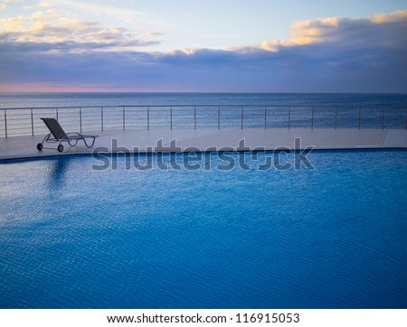 Low season at a sea resort; empty deck chair at a poolside overlooking the sea