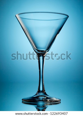 One empty martini glass on blue background