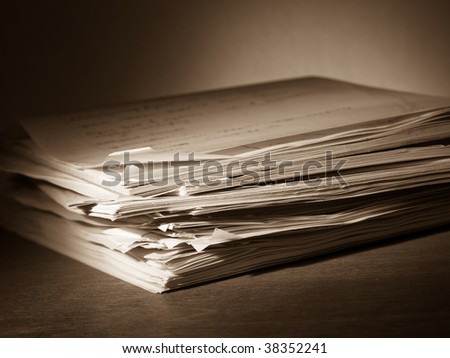 Heap of papers with a writing pad on top, toned