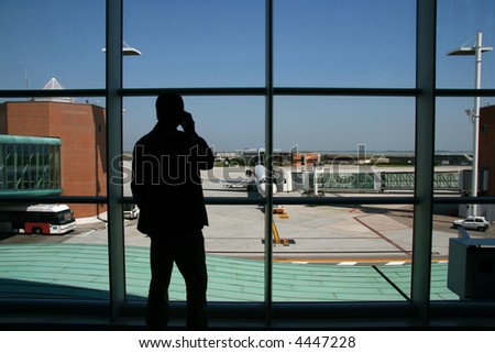 The silhouette of a businessman on the phone awaiting for his flight gate opening