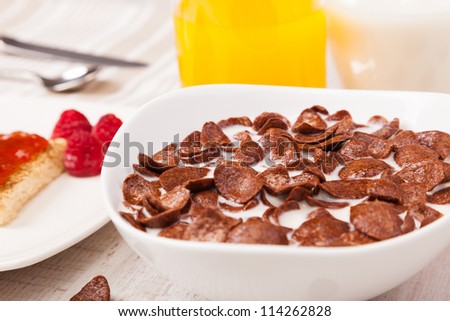 healthy breakfast with bowl of chocolate cereal and milk, toast with jam and fruit juice