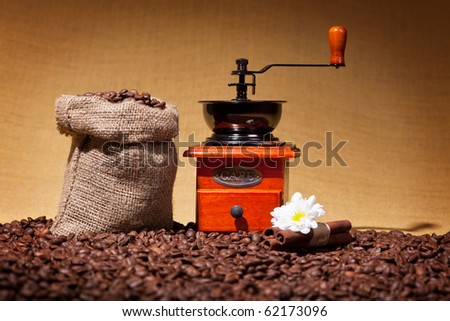 Vintage coffee grinder and burlap sack on roasted beans