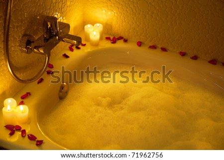 Romantic bathtub ready with candlelight and red petals