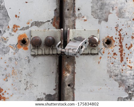 A strong lock on an old rusty metal door
