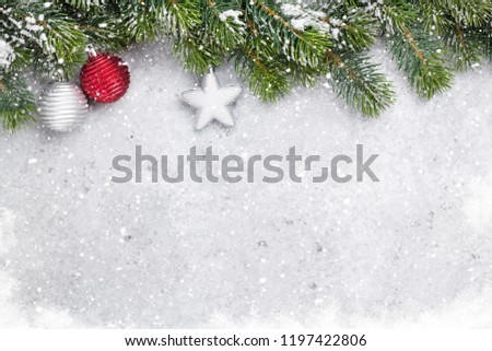 Christmas fir tree branch covered by snow and bauble decor on stone background. Xmas backdrop for your greeting card with space for text