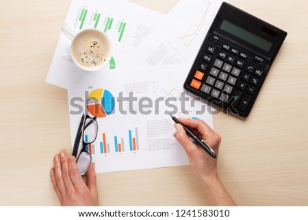 Woman working with reports and charts over wooden office desk. Top view