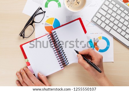 Woman working with reports and charts over wooden office desk. Top view with space for your text