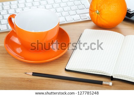 Coffee cup, orange fruit and office supplies on wooden table