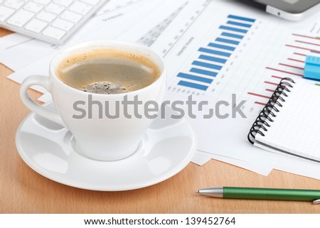 Coffee cup on contemporary workplace with financial papers, computer and office supplies