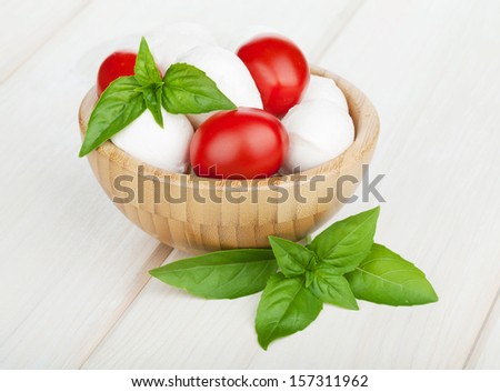 Mozzarella cheese with cherry tomatoes and basil on white wood table
