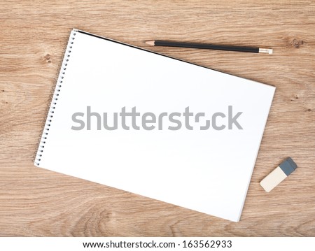 Blank Notepad, Pencil And Eraser On The Wooden Table. View From Above