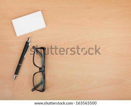 Blank business cards with pen and glasses on wooden office table with copy space