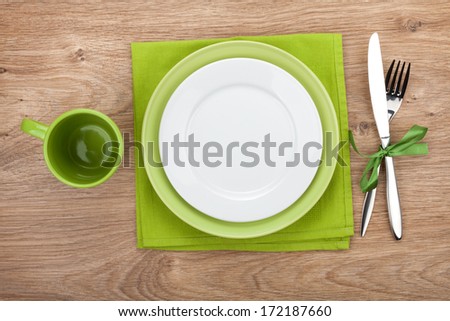 Fork with knife, blank plates, empty cup and napkin. On wooden table background