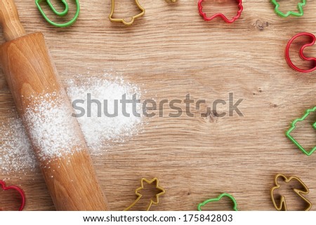 Rolling pin with flour and cookie cutters on wooden table. View from above with copy space