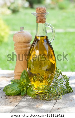 Olive oil bottle, pepper shaker and herbs on wooden table