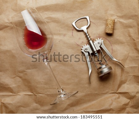 Wine glass, cork and corkscrew with red wine stains on brown paper background