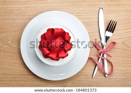 Valentine\'s day gift box on plate and silverware. View from above on wooden table background