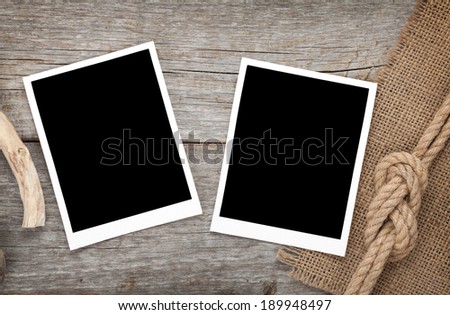 Blank photo frames with ship rope over wooden background