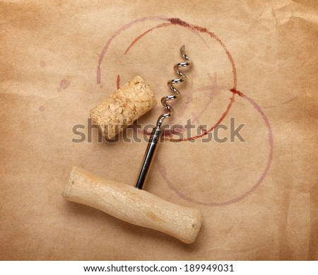 Cork and corkscrew with red wine stains on brown paper background