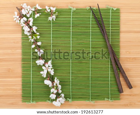Chopsticks and sakura branch over bamboo mat. Isolated on white background