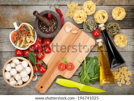 Fresh ingredients for cooking: pasta, tomato and spices over wooden table background with copy space
