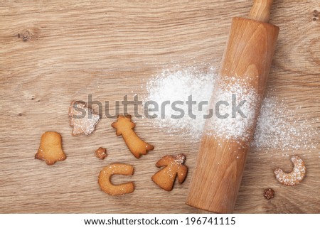 Rolling pin with flour and cookies on wooden table. View from above