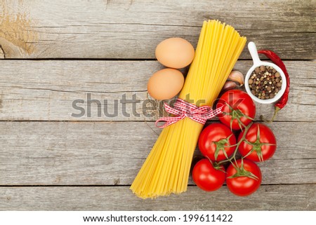 Pasta, tomatoes, eggs and spices on wooden table background