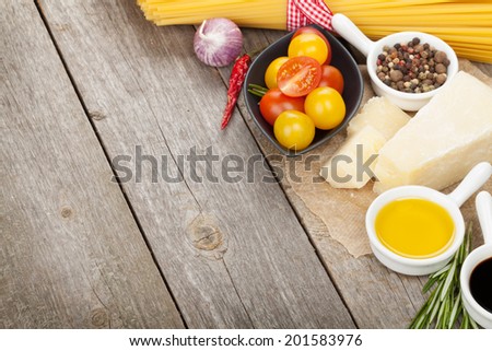 Herbs, spices, tomatoes and cheese on wooden table with copy space