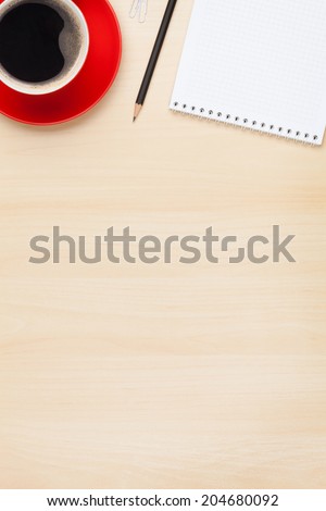 Office table with notepad and coffee cup. View from above with copy space