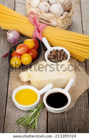 Parmesan cheese, pasta, tomatoes, vinegar, olive oil, herbs and spices on wooden table background