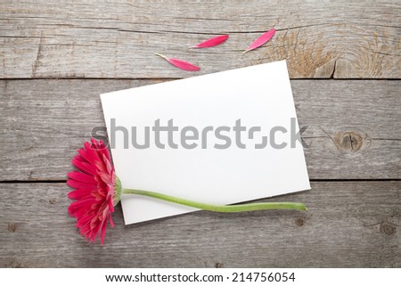 Purple gerbera flower and blank greeting card on wooden table