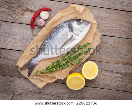 Fresh dorado fish cooking with spices and condiments on wooden table