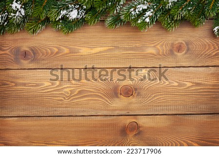 Christmas fir tree with snow on rustic wooden board with copy space