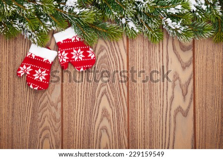 Christmas mitten decor and snow fir tree over wooden background with copy space