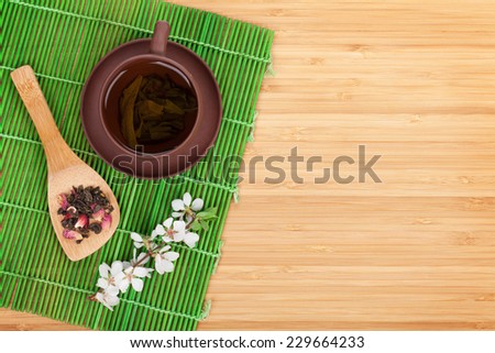 Japanese green tea and sakura branch over mat and bamboo table with copy space
