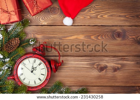 Christmas background with clock, snow fir tree and gift boxes over wood