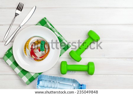 Dumbells and healthy food over wooden background. View from above with copy space