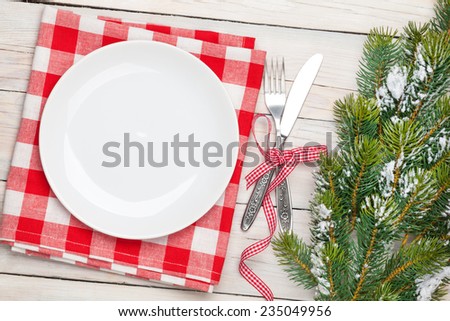 Empty plate, silverware and christmas tree. View from above over white wooden table background