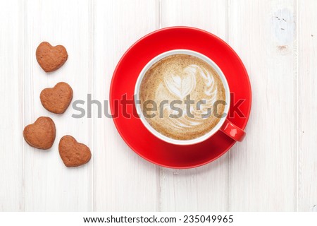 Valentines day heart shaped cookies and red coffee cup. View from above over white wooden table