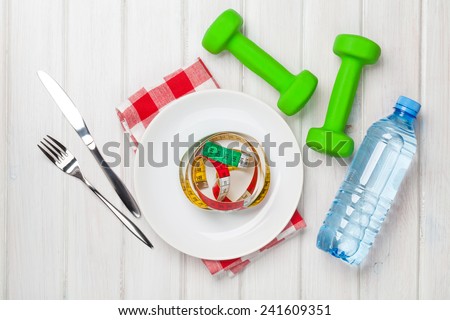 Dumbells and healthy food over wooden background. View from above