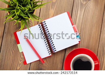 Office table with flower, blank notepad and coffee cup. View from above with copy space