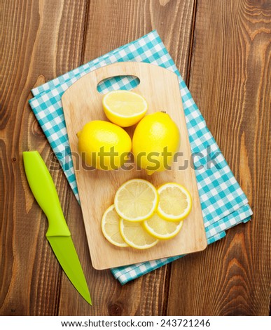 Sliced lemon fruits on cutting board over wooden table. View from above