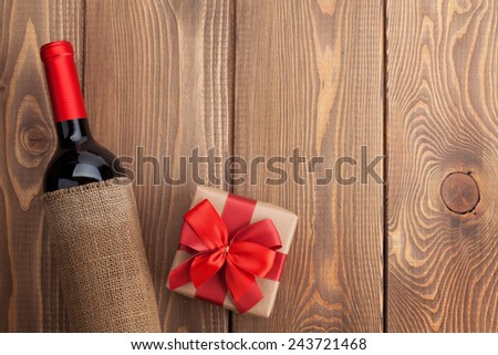 Red wine bottle and valentines day gift box. Over rustic wooden table background with copy space